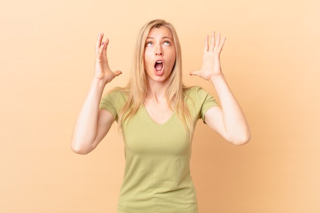 Jeune femme blonde criant avec les mains en l'air