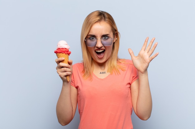 Jeune femme blonde crier avec les mains en l'air, se sentir furieux, frustré, stressé et bouleversé