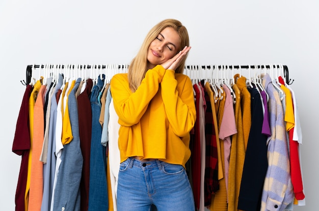 Jeune femme blonde dans un magasin de vêtements faisant un geste de sommeil dans une expression adorable