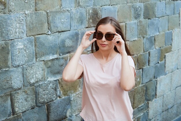 Jeune femme blonde dans un t-shirt rose avec des lunettes de soleil