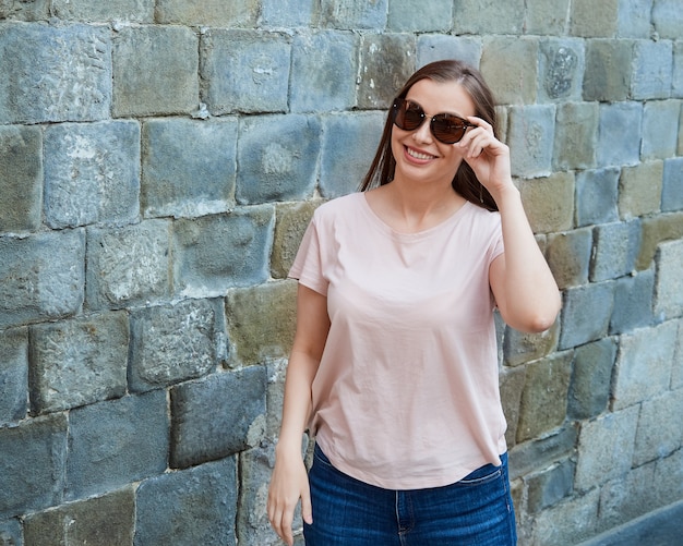 Jeune femme blonde dans un t-shirt rose avec des lunettes de soleil