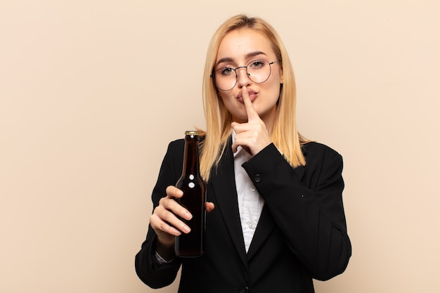 Jeune femme blonde demandant le silence et la tranquillité, faisant des gestes avec le doigt devant la bouche, disant chut ou gardant un secret