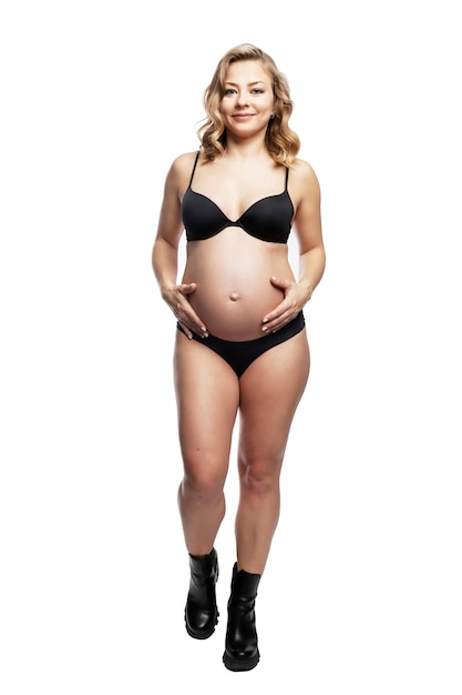 Jeune femme blonde enceinte en lingerie noire et chaussures rugueuses.