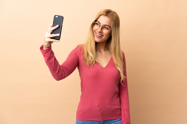 Jeune femme blonde sur un espace isolé faisant un selfie