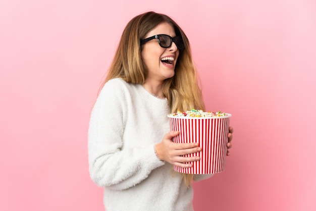 Jeune femme blonde sur un espace isolé avec des lunettes 3D et tenant un grand seau de pop-corn