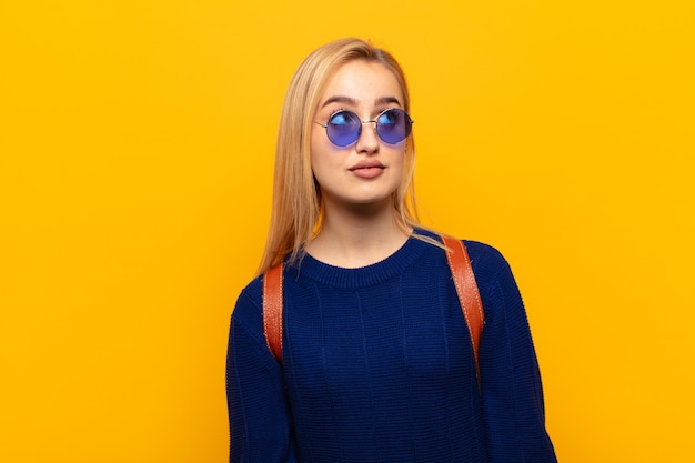 Jeune femme blonde avec une expression inquiète, confuse, désemparée, regardant pour copier l'espace, doutant