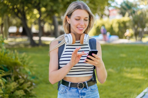 Jeune femme blonde à l'extérieur à l'aide de téléphone portable