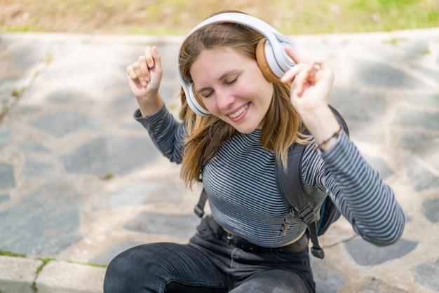 Jeune femme blonde à l'extérieur, écoutant de la musique