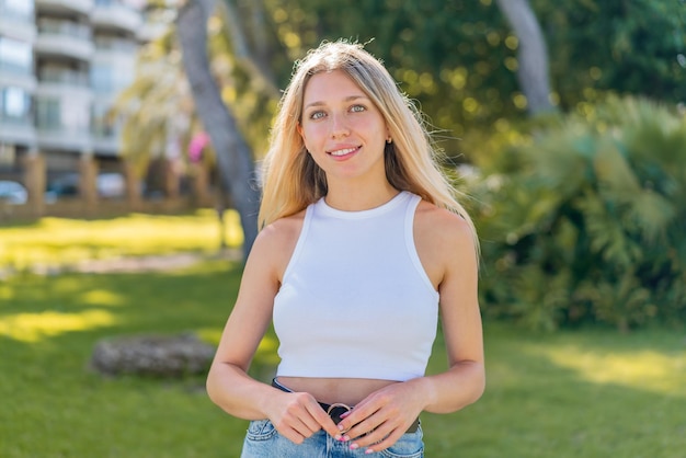 Jeune femme blonde à l'extérieur avec une expression heureuse