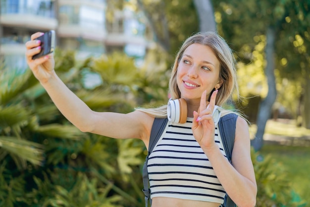 Jeune femme blonde à l'extérieur faisant un selfie