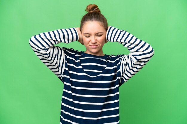 Jeune femme blonde sur un fond de clé chrome isolé frustrée et couvrant les oreilles