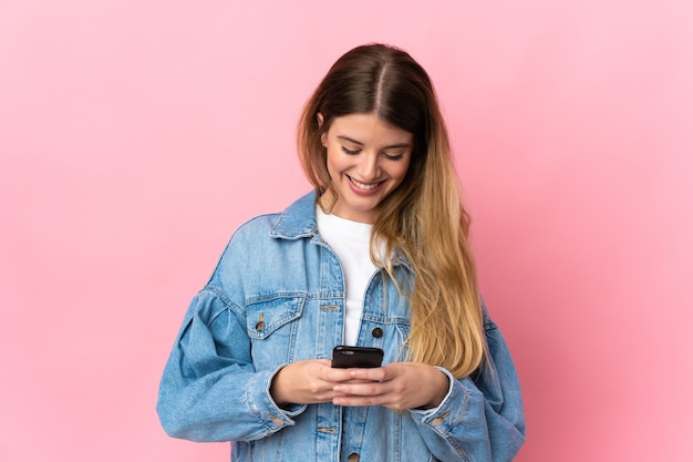 Jeune femme blonde sur fond isolé l'envoi d'un message ou d'un e-mail avec le mobile