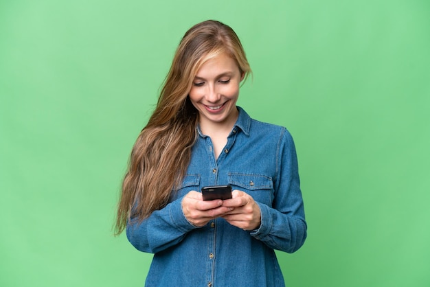 Jeune femme blonde sur fond isolé envoyant un message avec le mobile