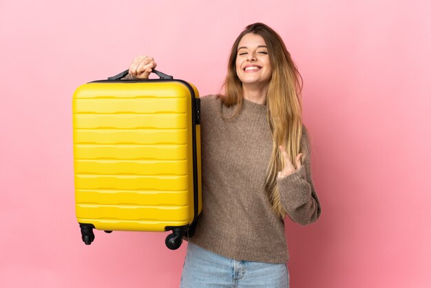 Jeune femme blonde sur fond isolé en vacances avec valise de voyage