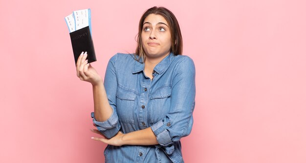 Jeune femme blonde haussant les épaules, se sentant confus et incertain, doutant avec les bras croisés et regard perplexe