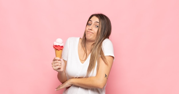 Jeune femme blonde haussant les épaules, se sentant confus et incertain, doutant des bras croisés et regard perplexe