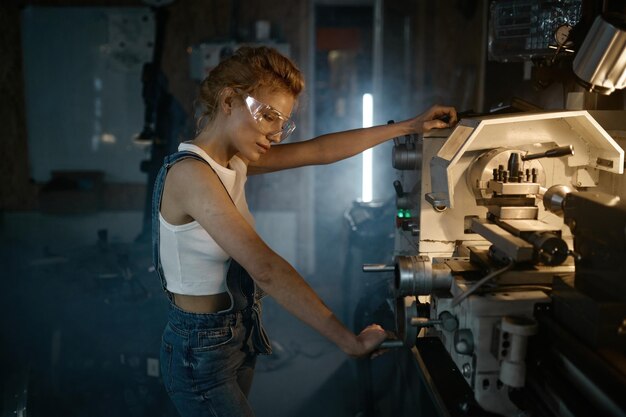 Photo jeune femme blonde ingénieur en mécanique travaillant sur la machine de tour