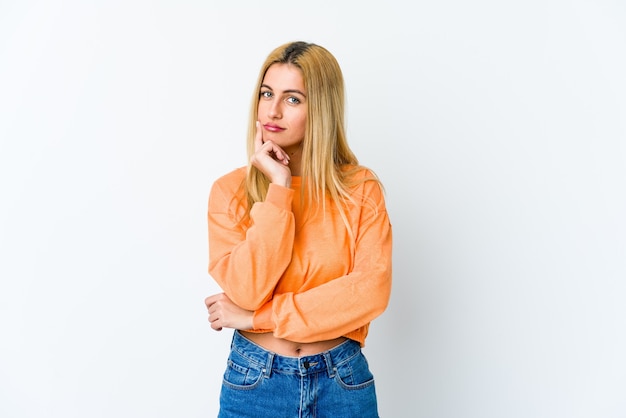 Jeune femme blonde isolée sur blanc à la recherche de côté avec une expression douteuse et sceptique.