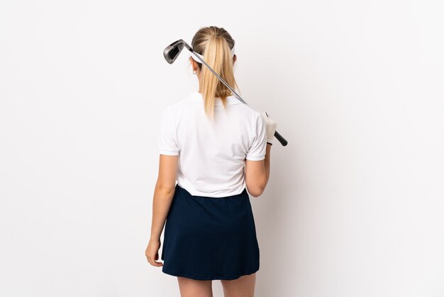 Jeune femme blonde isolée sur fond blanc à jouer au golf et en position arrière