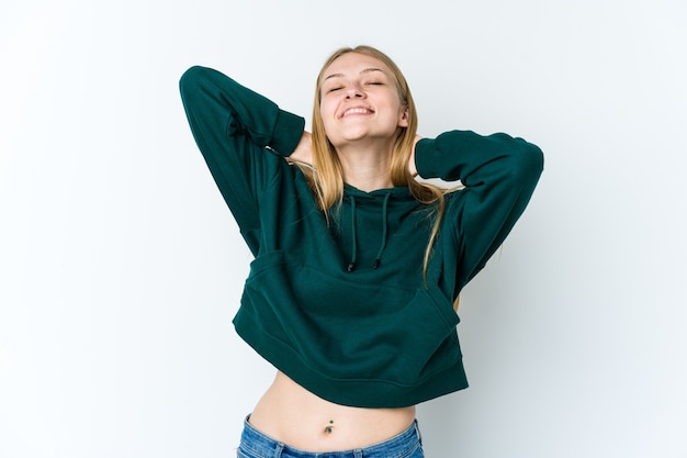 Jeune femme blonde isolée sur fond blanc se sentir confiant, avec les mains derrière la tête.