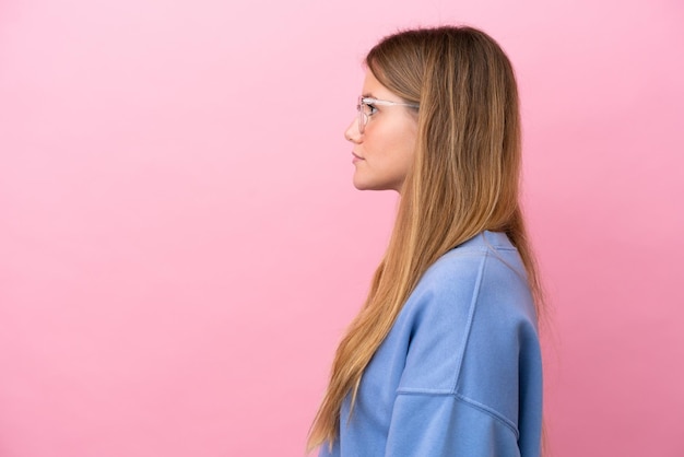 Jeune femme blonde isolée sur fond rose avec des lunettes