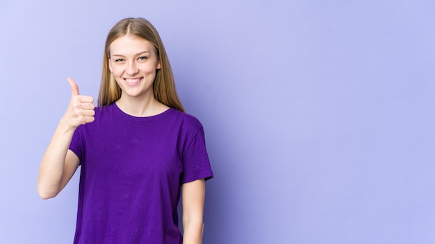 Jeune femme blonde isolée sur fond violet souriant et levant le pouce vers le haut