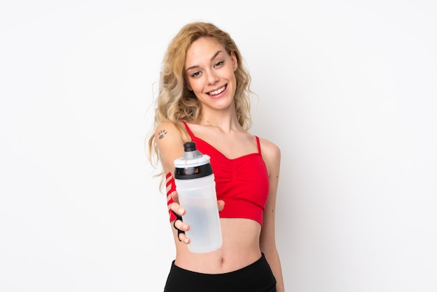 Jeune femme blonde isolée sur un mur blanc avec une bouteille d'eau de sport