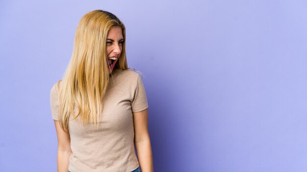 Jeune femme blonde isolée sur violet criant très en colère, concept de rage, frustré.