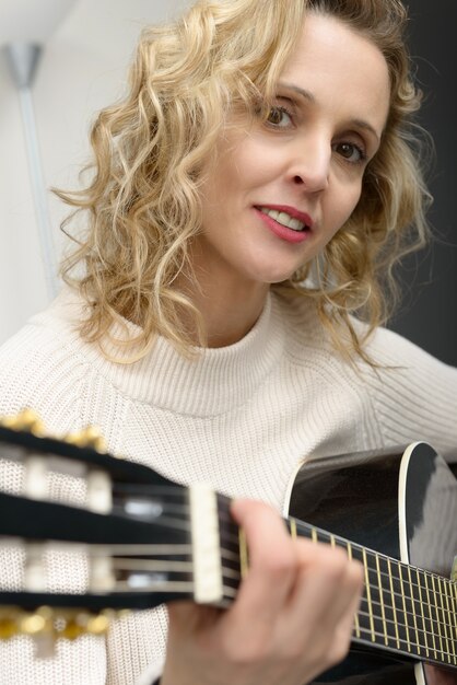 Jeune femme blonde jouant de la guitare acoustique
