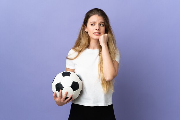 Jeune femme blonde joueur de football posant isolé contre le mur blanc