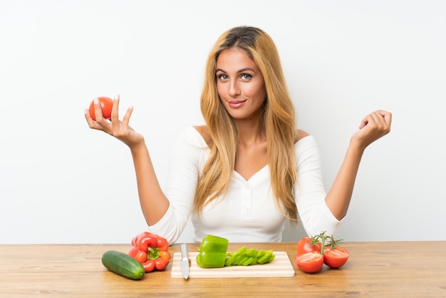 Jeune femme blonde avec des légumes dans une table