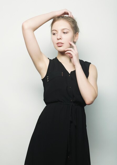 Jeune femme blonde de mode en robe noire qui pose en studio