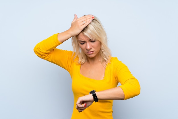 Jeune femme blonde avec une montre au poignet et surprise