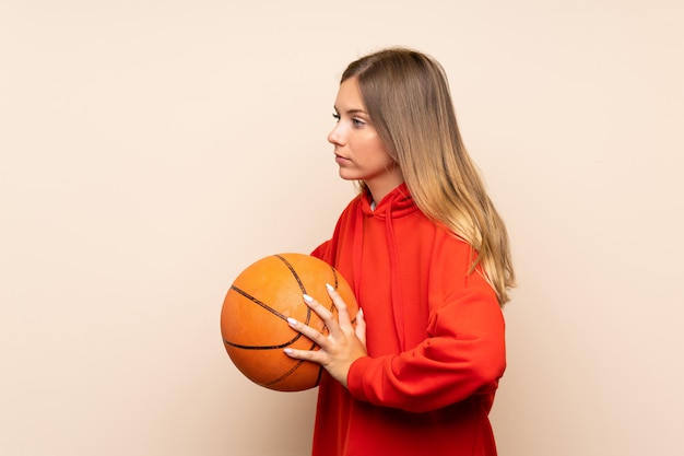 Jeune femme blonde sur un mur isolé avec ballon de basket
