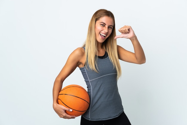 Jeune femme blonde sur mur isolé jouant au basket et fier de lui