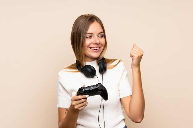 Jeune femme blonde sur mur isolé jouant à des jeux vidéo