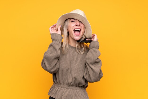 Jeune femme blonde sur mur jaune isolé