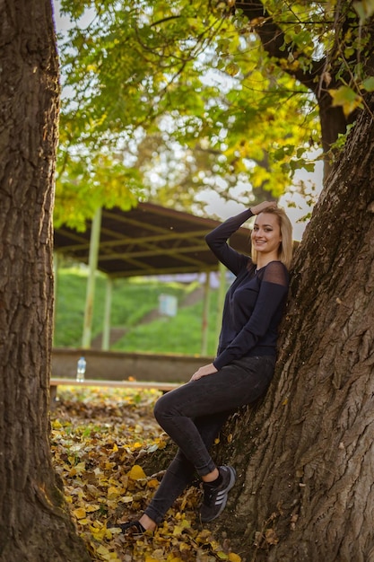 Photo une jeune femme blonde en noir pose pour la caméra dans le parc d'automne.