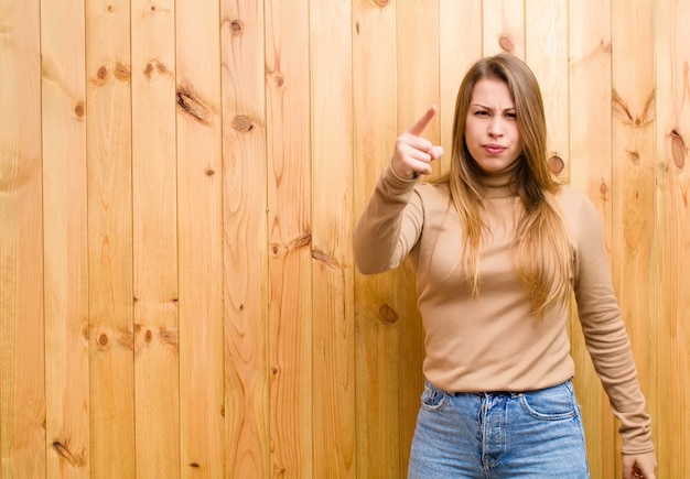 Jeune femme blonde pointant avec une expression agressive en colère ressemblant à un patron furieux et fou