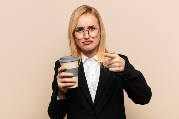 Jeune femme blonde pointant vers l'avant à la caméra avec les deux doigts et une expression de colère, vous disant de faire votre devoir