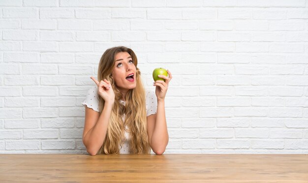 Jeune femme blonde avec une pomme qui pense