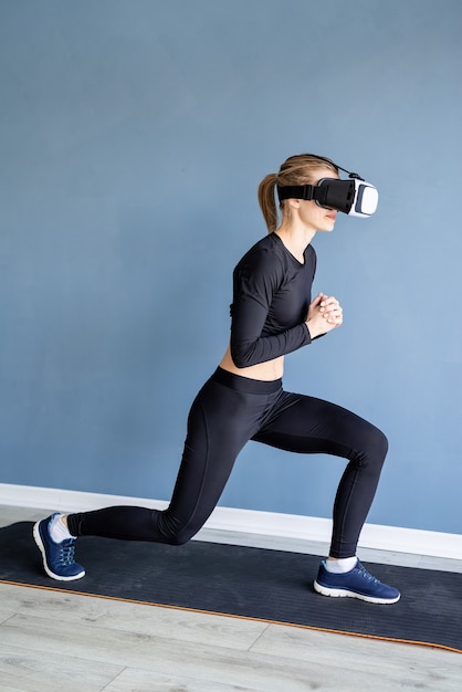 Jeune femme blonde portant des lunettes de réalité virtuelle faisant une fente avant