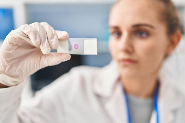 Jeune femme blonde portant l'uniforme scientifique à la recherche d'un échantillon au laboratoire