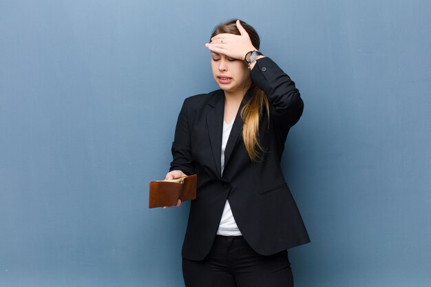 Jeune femme blonde avec un portefeuille contre le mur de grunge