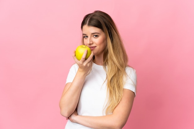 Jeune femme blonde posant isolée contre le mur rose