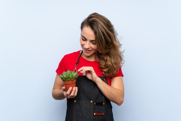 Jeune femme blonde prenant un pot de fleurs