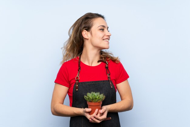 Jeune femme blonde prenant un pot de fleurs