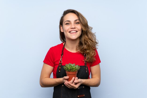 Jeune femme blonde prenant un pot de fleurs