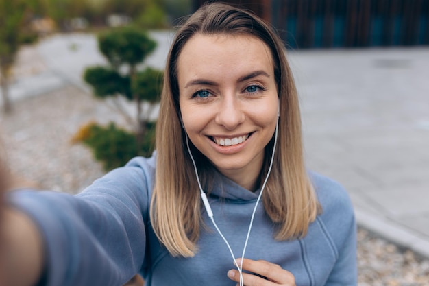 Jeune femme blonde prenant selfie à l'extérieur