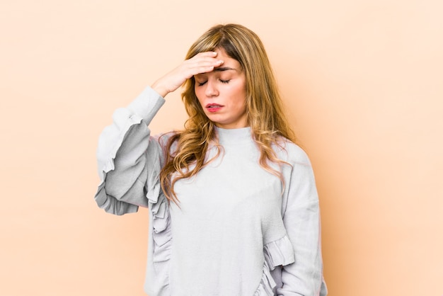 Jeune femme blonde de race blanche ayant mal à la tête, touchant le devant du visage.